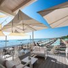 Terrazza sul mare con ombrelloni, sedie e vista su spiaggia attrezzata.
