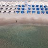 Spiaggia con ombrelloni blu e bianchi, persona vicino all'acqua.