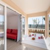 Terrazza con tavolo apparecchiato e soggiorno interno con divano rosso.