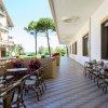 Una terrazza con tavoli e sedie, palme e vista su alberi verdi e cielo azzurro.