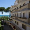 Edificio a più piani con balconi, vista mare e alberi sullo sfondo.