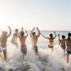 Persone che corrono nel mare con entusiasmo al tramonto.