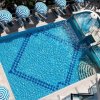 Vista dall'alto di una piscina con ombrelloni a righe blu e bianche disposti intorno.