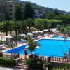 Piscina all'aperto circondata da sdraio e ombrelloni, in un'area verde con edifici vicini.