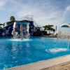 Piscina con fontane d'acqua e scivolo blu sullo sfondo.