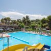 Piscina all'aperto con scivoli e sedie a sdraio, circondata da alberi.