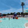 Ampia piscina con scivolo colorato centrale. Sedie a sdraio e ombrelloni circondano l'area.