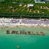 Spiaggia affollata con persone che formano la scritta 