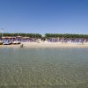 Una spiaggia affollata con pedalò sulla riva.