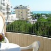 Un balcone con tavolo e fiori offre una vista sul mare e su edifici moderni.
