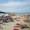 Spiaggia affollata con lettini e ombrelloni, persone che prendono il sole.