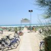 Spiaggia sabbiosa con biciclette e ombrelloni verdi.