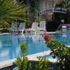 Piscina con sdraio bianche e ingresso con insegna 