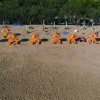 Spiaggia sabbiosa con ombrelloni e sdraio arancioni.