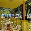 Tavolo con tovaglia a fiori su veranda gialla, vista mare e alberi.
