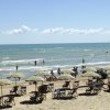 Spiaggia con ombrelloni, sedie e bagnanti.