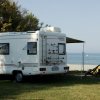 Camper bianco parcheggiato vicino al mare.