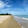 Spiaggia con mare calmo e cielo blu.