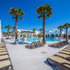 Piscina circondata da palme e lettini, sotto un cielo blu limpido.