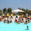 Piscina affollata con attività animate da istruttori in magliette gialle.