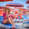Donna seduta sotto ombrelloni colorati in spiaggia.